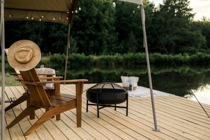 A wooden deck with a chair, a grill, and a table.