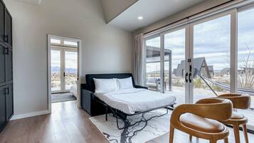 Un dormitorio moderno con cama, zona de estar con sillas y un ventanal con vistas al paisaje desértico.