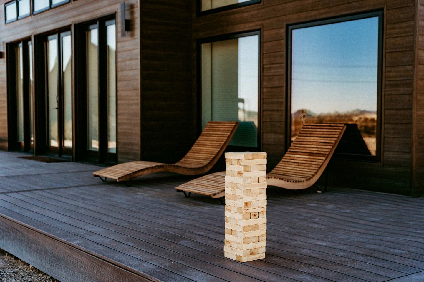 A wooden deck with two lounge chairs and a stack of wooden blocks.