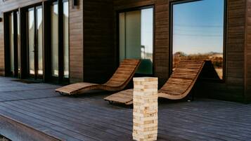 A wooden deck with two lounge chairs and a stack of wooden blocks.