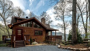 Une cabane en bois avec un porche, une cheminée et une allée gravillonnée.