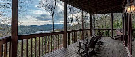 Una terraza de madera con banco y mesa, con vistas a un paisaje montañoso.