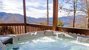 Un bain à remous avec vue sur les montagnes, entouré d’une terrasse en bois.