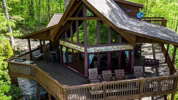 Une cabane dotée d’une terrasse, d’un espace salon extérieur et de fondations en pierre.