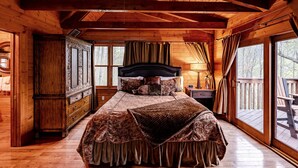 Une chambre à coucher dans une cabane en bois, avec un lit, une table de chevet, une commode et une fenêtre donnant sur une terrasse.