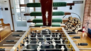 A foosball table in a room with a door, a window, and a brick wall. - Unbelievable Cabin with Amazing Sights and Fire Pit in Winhall, Vermont (Winhall)