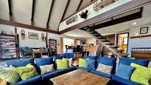 A spacious living room with a large sectional sofa, a wooden coffee table, and a staircase leading to an upper level. - Unbelievable Cabin with Amazing Sights and Fire Pit in Winhall, Vermont (Winhall)