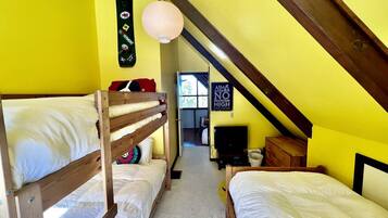 A dormitory room with bunk beds, a television, and a sign on the wall.