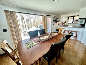 Un comedor con una mesa de madera, sillas y vistas a un bosque a través del ventanal.