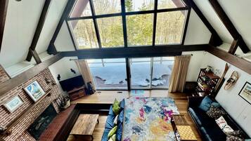 A loft-style room with a large skylight, a fireplace, a sofa, a coffee table, and a bookshelf.