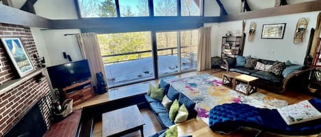 Un amplio salón con un ventanal grande, una chimenea, un conjunto de sofás y una mesa de centro.