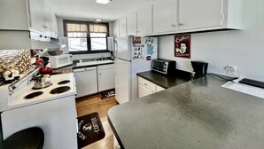 A compact kitchen with white cabinets, a stove, microwave, and a coffee sign. - Unbelievable Cabin with Amazing Sights and Fire Pit in Winhall, Vermont (Winhall)