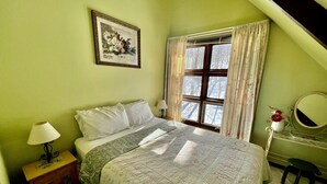 A bedroom with a bed, a nightstand, a dresser, a mirror, and a window with curtains. - Unbelievable Cabin with Amazing Sights and Fire Pit in Winhall, Vermont (Winhall)