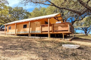 Une cabane en bois d’un seul étage, dotée d’un porche couvert, d’une petite terrasse et de fondations en pierre.