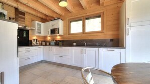 A modern kitchen with white cabinets, a stainless steel range hood, and a wooden ceiling. - Luxury mountain chalet for 8 people Saint Gervais close to amenities (Saint-Gervais-les-Bains)