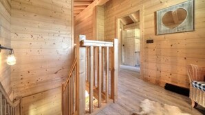 A wooden interior with a staircase, a heart-shaped wall decoration, and a wicker chair. - Luxury mountain chalet for 8 people Saint Gervais close to amenities (Saint-Gervais-les-Bains)