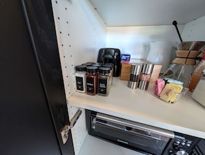 Eine Küchenzeile mit Kaffeemaschine, Salz, Paprika, schwarzem Pfeffer und einem Geschirrgestell.