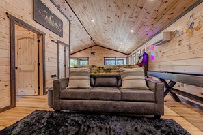 A cozy cabin interior with a leather sofa, a fur throw, and a wooden ceiling. - Charming Mountain Cabin with Hot Tub & Game Loft near Pigeon Forge, Tennessee (Sevierville)