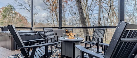 An outdoor deck with a fire pit, seating area, and a hot tub.