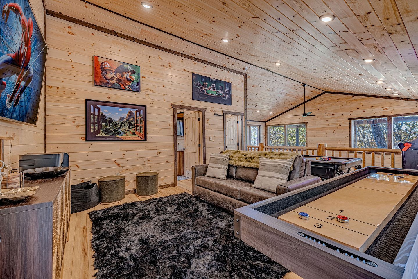 A wooden cabin interior with a pool table, sofa, and artwork on the walls.
