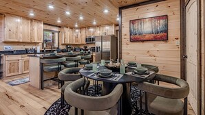 Un interior de madera con comedor, cocina y un cuadro en la pared.