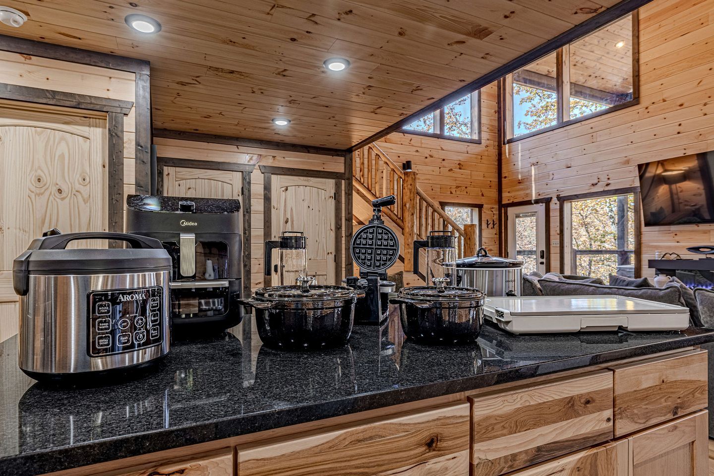 A kitchen with a granite countertop, a waffle maker, a coffee maker, and a slow cooker.