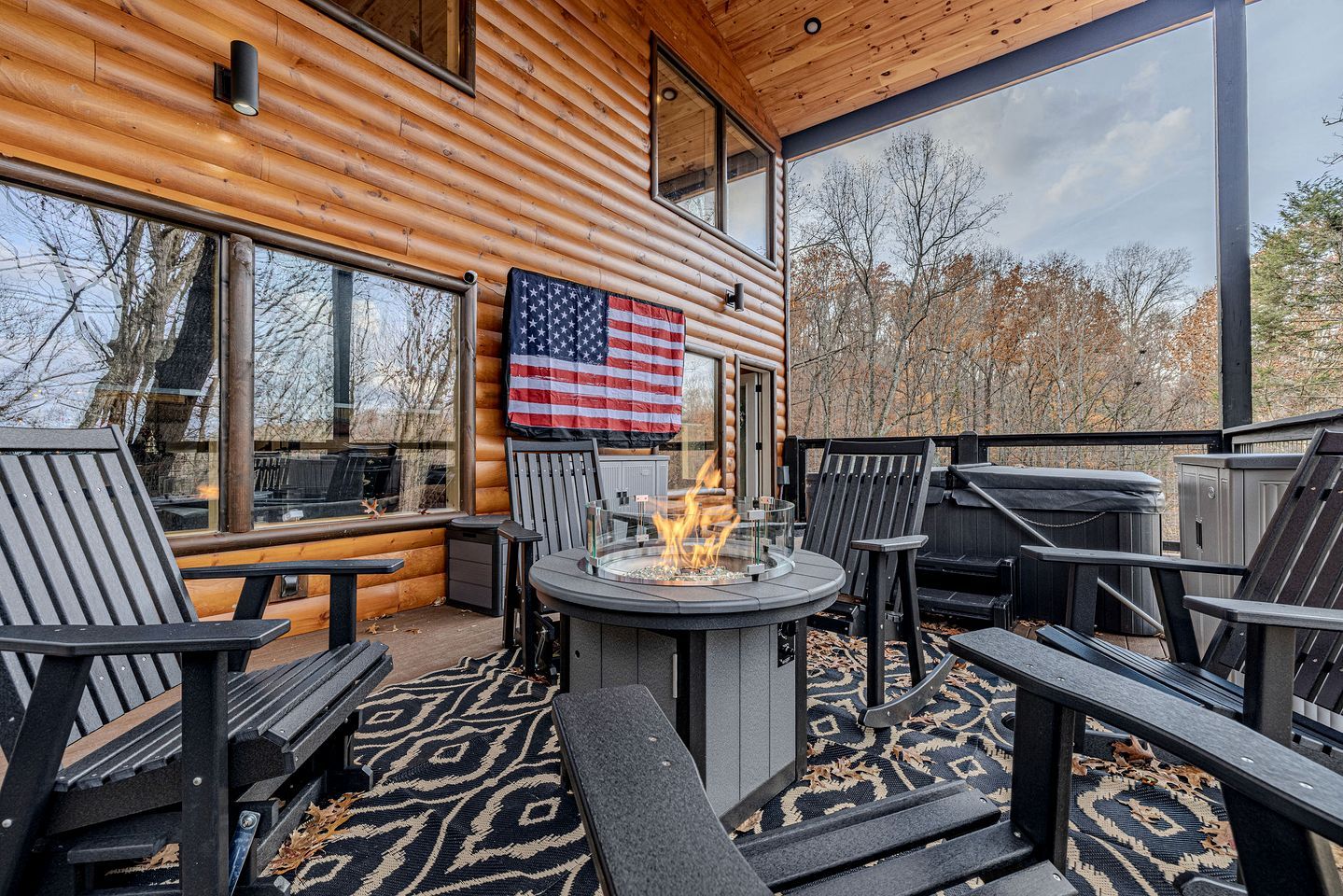 A log cabin with a fire pit, outdoor seating, and an American flag.