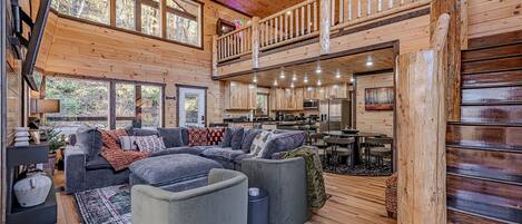 A spacious cabin interior with a large living area, a kitchen, and a balcony.