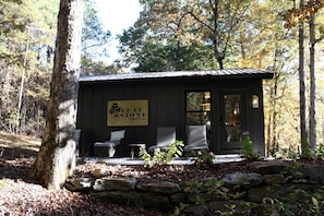 A small building with a sign reading 'Leaf & Stone Spa' and two wicker chairs outside. - Wonderful Tiny House with Outdoor Living Areas in Alabama (Scottsboro)