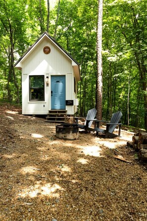 Une petite cabane avec une porte bleue, entourée d’arbres.