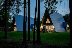 A modern, triangular-shaped building with a glass facade and a picnic table outside.