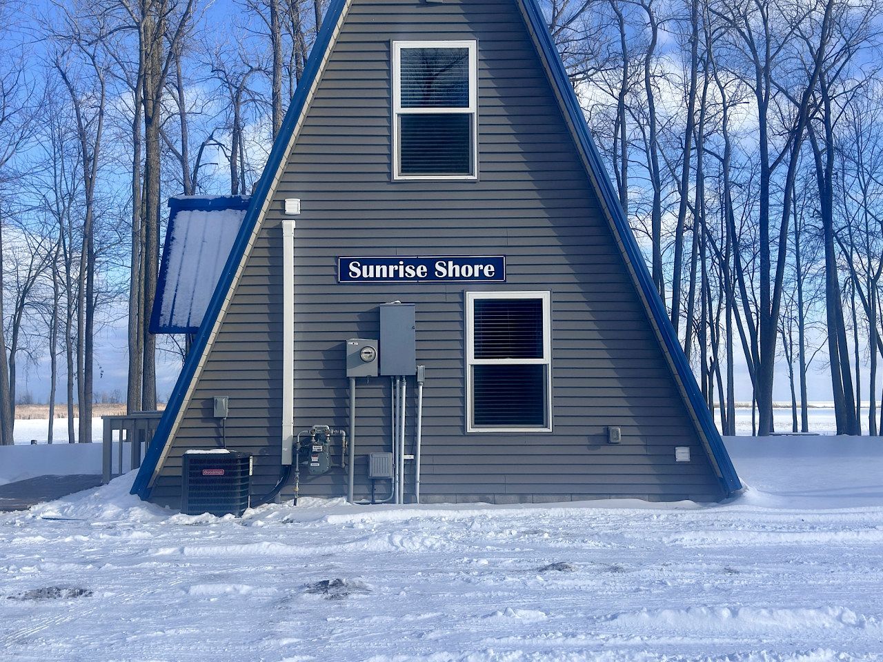 Un bâtiment triangulaire sur lequel on peut lire l’inscription « Sunrise Shore », entouré de neige et d’arbres sans feuilles.