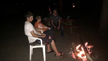 Tres personas sentadas al aire libre de noche junto a una fogata.