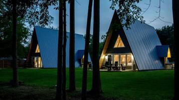 Un edificio moderno de forma triangular con fachada de vidrio y una mesa de picnic afuera.