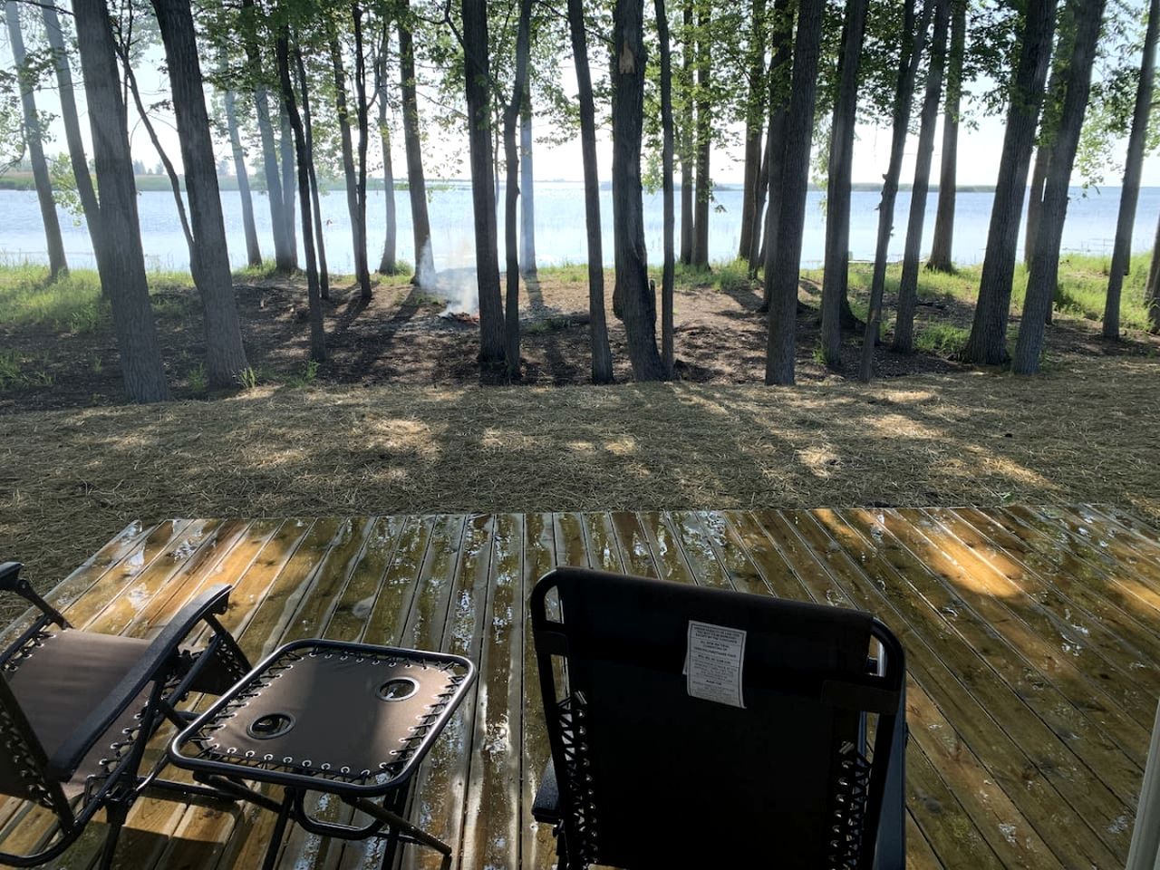 Una terraza con dos sillas, con vista a un área boscosa y una masa de agua.