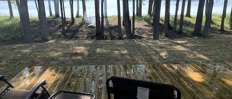 Une terrasse avec deux chaises, donnant sur une zone boisée et un plan d’eau.