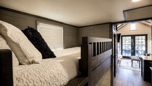 Un dormitorio con literas, una ventana con persianas y vistas a un patio exterior.