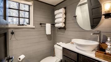 A bathroom with a toilet, sink, and window.