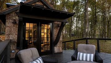 A wooden deck with outdoor seating and a glass door entrance to a building.