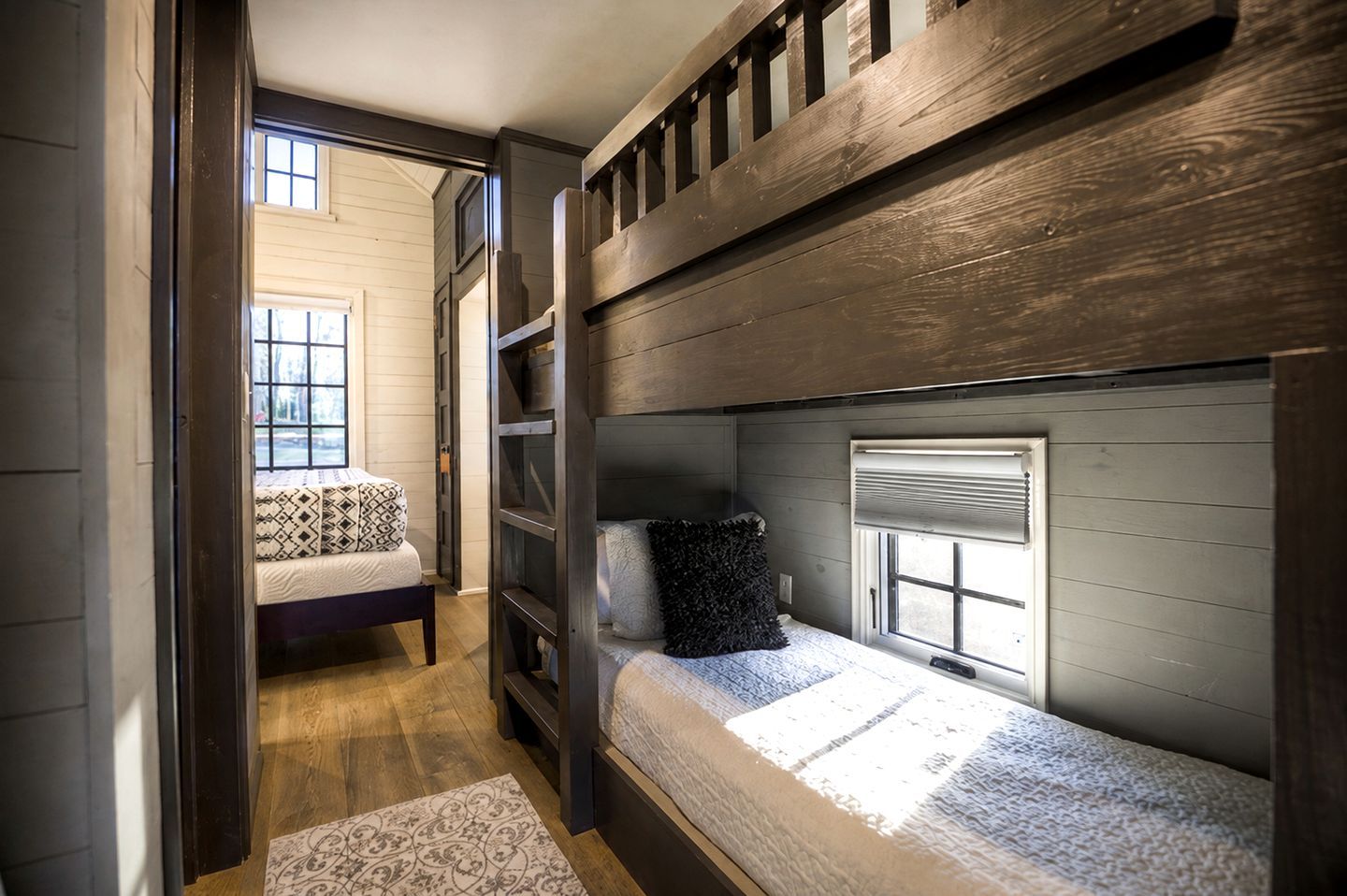 Camera con letto a castello, finestra, comodino e tappeto decorato.