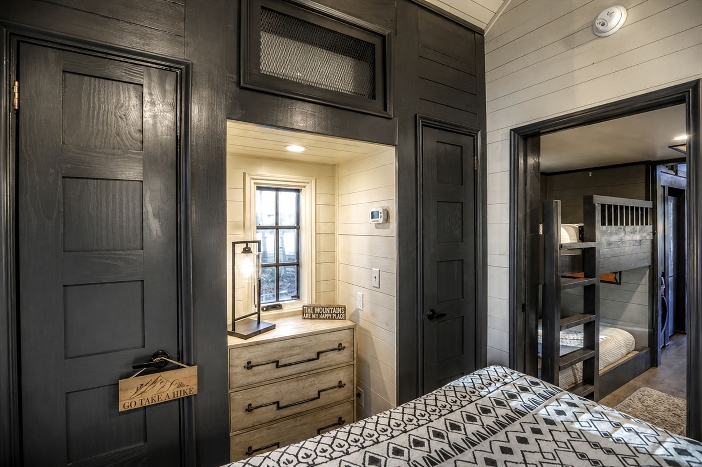 A bedroom with a bed, a dresser, a mirror, and a window.
