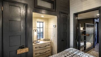 A bedroom with a bed, a dresser, a mirror, and a window.