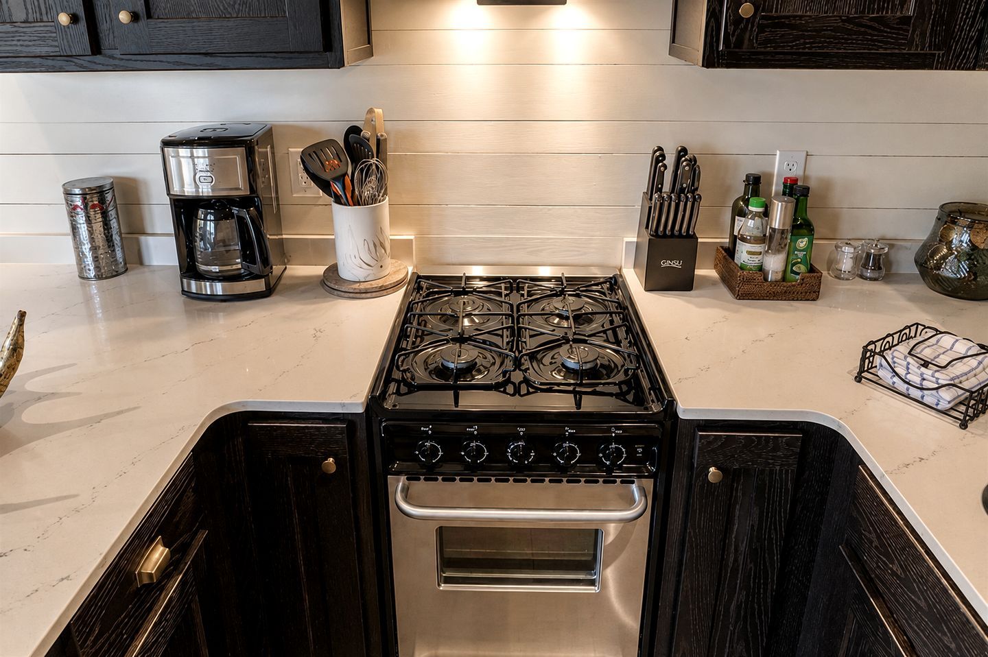 A kitchen with a gas stove, coffee maker, and various kitchen utensils.