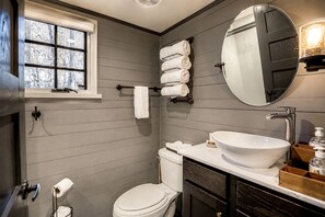 A bathroom with a toilet, sink, and window.