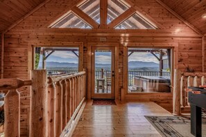 A wooden cabin interior with a central door leading to a balcony with a mountain view. - Modern Mountain Cabin Retreat with Game Room and Outdoor Pool in Sevierville, Tennessee (Sevierville)