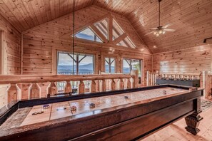 A wooden interior with a foosball table, large windows, and a balcony. - Modern Mountain Cabin Retreat with Game Room and Outdoor Pool in Sevierville, Tennessee (Sevierville)