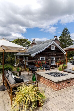 Une maison rustique en bois dotée d’un patio aménagé avec des meubles d’extérieur, un foyer et des plantes en pot.