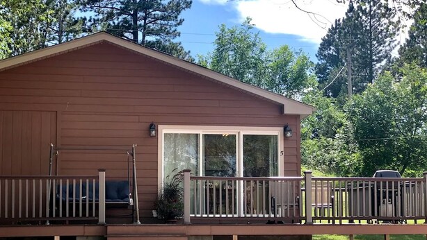 A cabin with a porch, a covered seating area, and a large window. - Sweet Cabin with Furnished Patio Suitable for Six in South Dakota (Hot Springs)