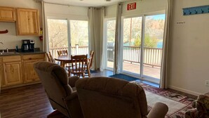 A living room with a dining area, a kitchen, and a balcony with a view. - Sweet Cabin with Furnished Patio Suitable for Six in South Dakota (Hot Springs)
