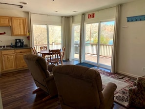 A living room with a dining area, a kitchen, and a balcony with a view. - Sweet Cabin with Furnished Patio Suitable for Six in South Dakota (Hot Springs)